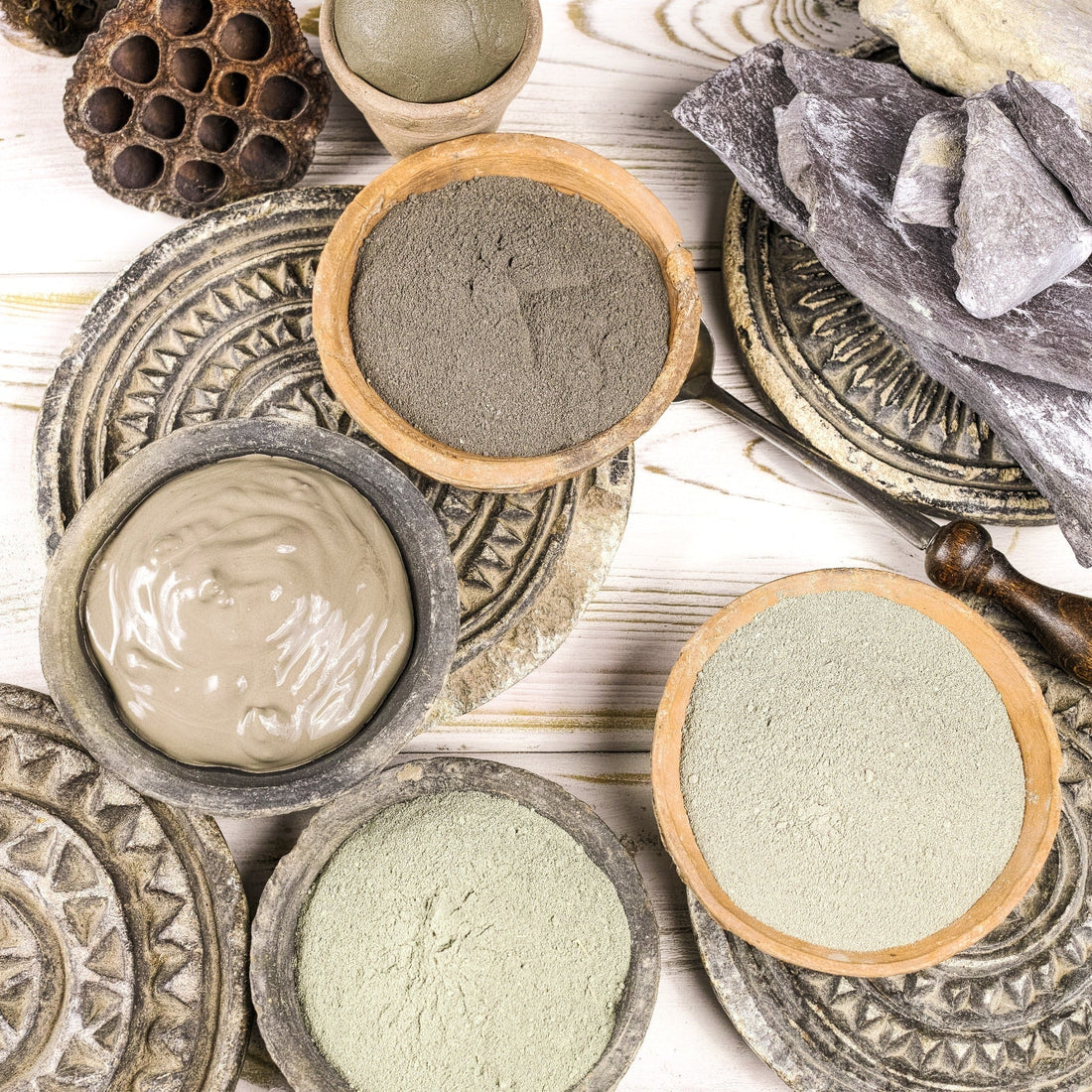 Beatuiful bowls spread out on wooden table containing french green clay and masks