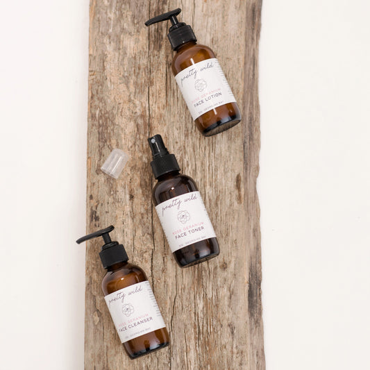 pretty wild face toner with cleanser and lotion on a rustic wooden plank on a creamy white background