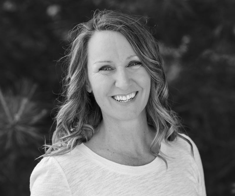 Natural skincare products formulator.A black and white photo of SiSi Georgian Bay founder Andrea Tranter smiling looking at the camera with trees in the background wearing a cream coloured cotton shirt