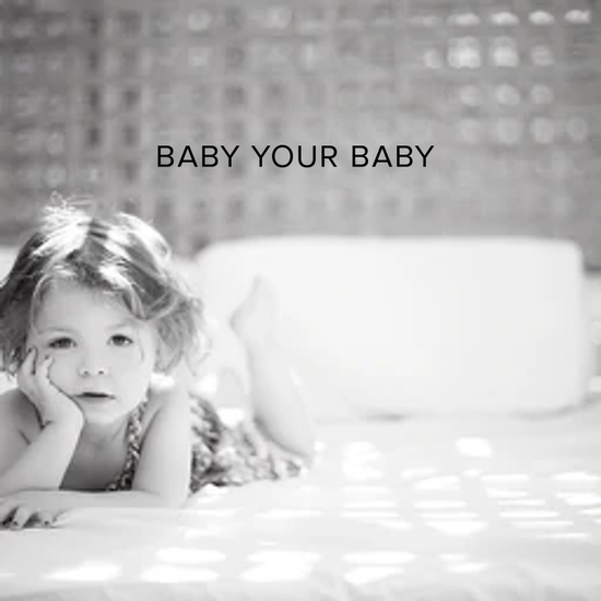 Natural skincare products. A grey scale photo of a cute girl approximately 1 -2 yrs. old laying on a bed with her chin in her hand leaning on her elbow with crisp white bedding and a lattice headboard behind her Black printed words that say baby your baby