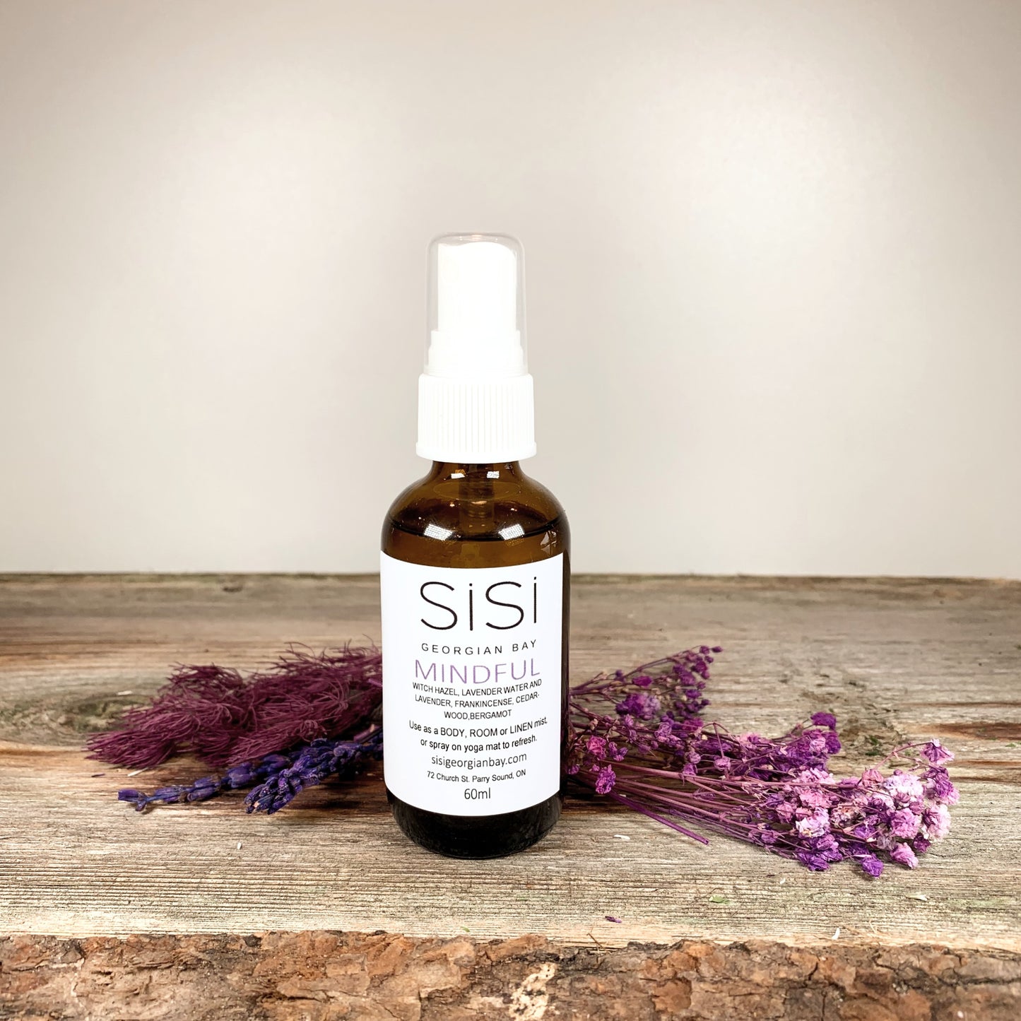 Aromatherapy Products - SiSi Georgian Bay Yoga Sprays in amber glass bottles on a rustic wooden live edge surface with flowers spread around the bottom