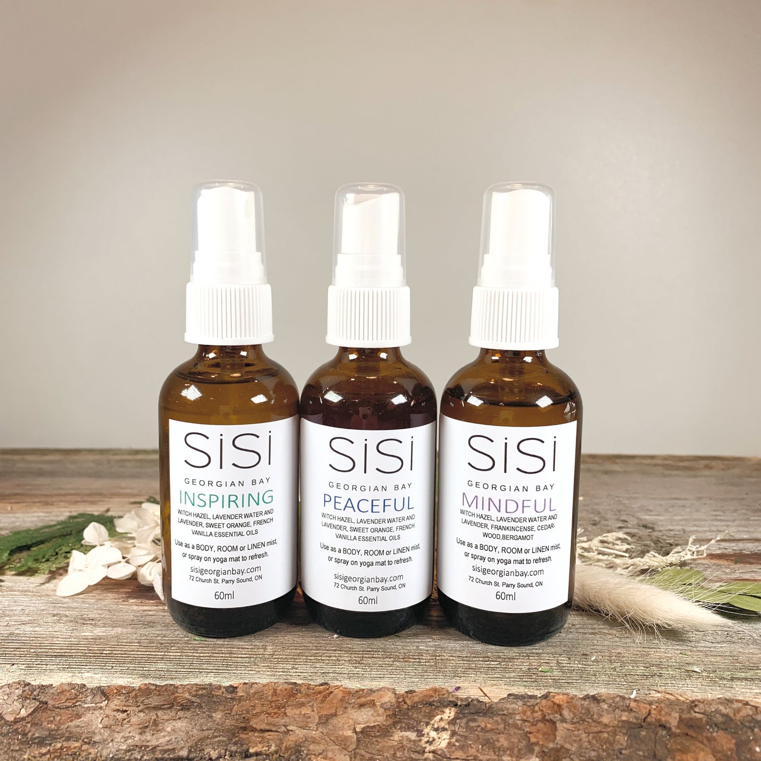 Natural skincare products - Aromatherapy Products - SiSi Georgian Bay Yoga Sprays in amber glass bottles  on a rustic wooden live edge surface with flowers and greenery spread around the bottom