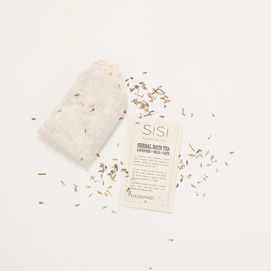 a pretty styled photo of a sisi georgian bay herbal bath tea in a muslin bag on a creamy background with lavender buds sprinkled around