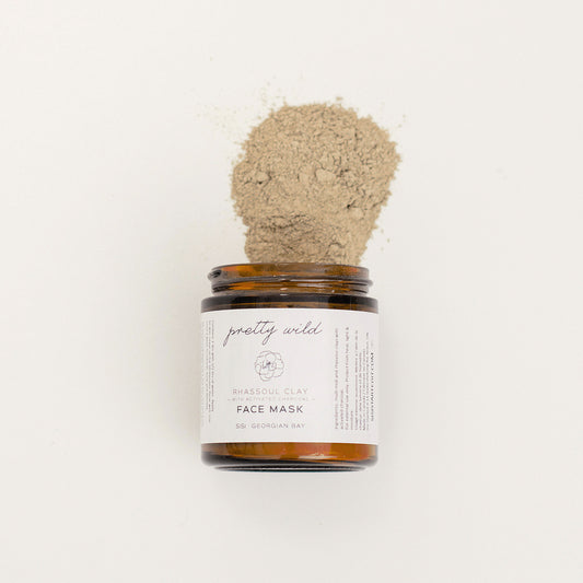 Clean beauty care products - SiSi Georgian Bay "pretty wild" face mask in an amber glass jar on it's side with the contents spilling out on a creamy white background
